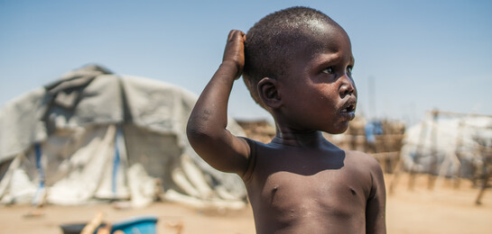 Ein Junge im Südsudan steht vor einem Flüchtlingszelt.