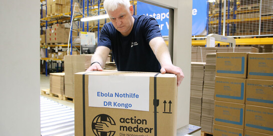 Ein Mitarbeiter von action medeor verpackt eine Hilfslieferung für die Ebola-Region