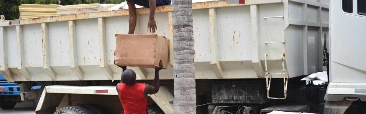 Helfer laden auf Haiti Säcke ab. Beide sind Betroffene des Hurrikan Matthew