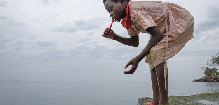 Ein Mädchen putzt sich die Zähne an einem See in Uganda Ein Mädchen putzt sich die Zähne an einem See in Uganda