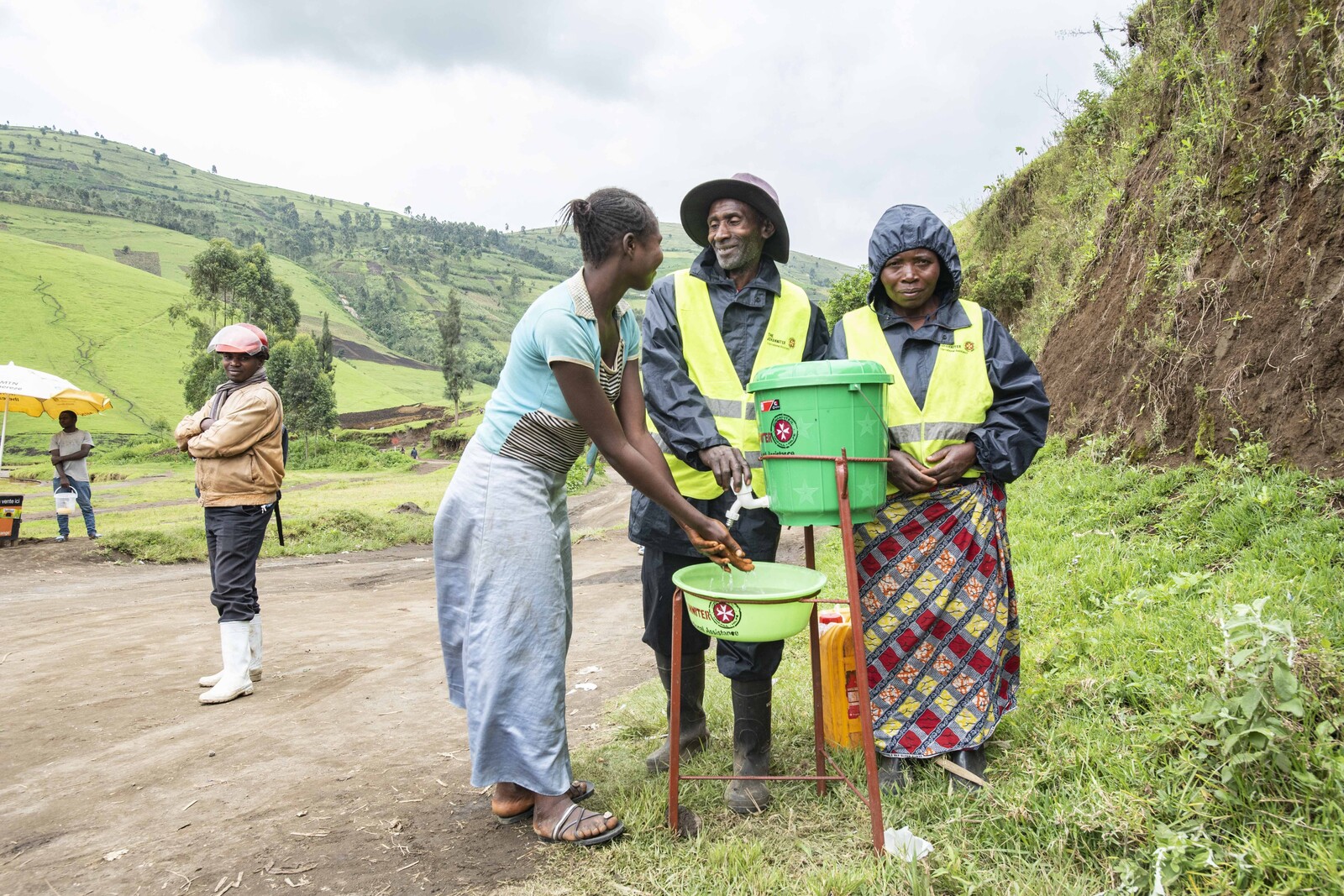 Zwei Frauen und Männer an einer Trinkwasserstation in der DR Kongo