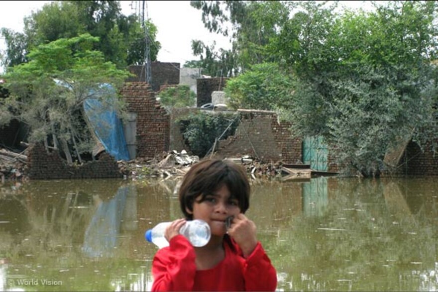 maedchen-flutgebiet Flut Pakistan: Mädchen mit Wasserflasche vor überschwemmtem Gebiet
