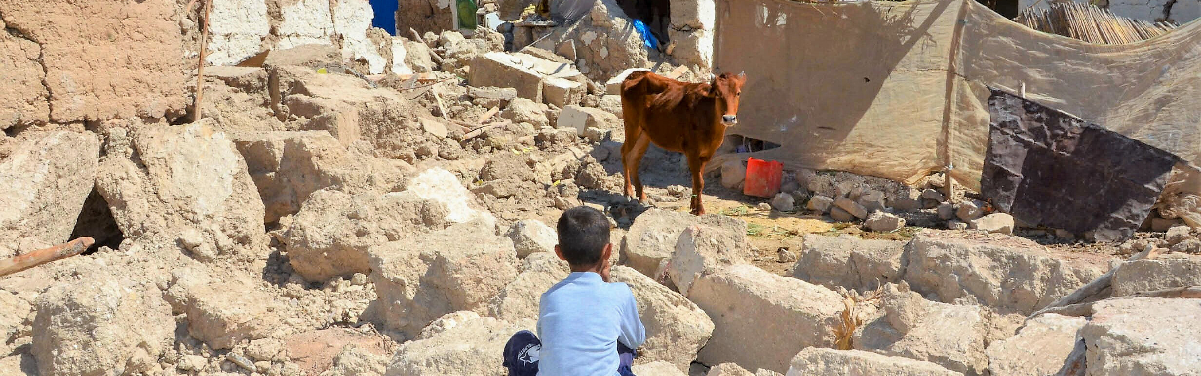 Ein Junge hockt nach dem Erdbeben in Marokko zwischen Trümmern zerstörter Häuser