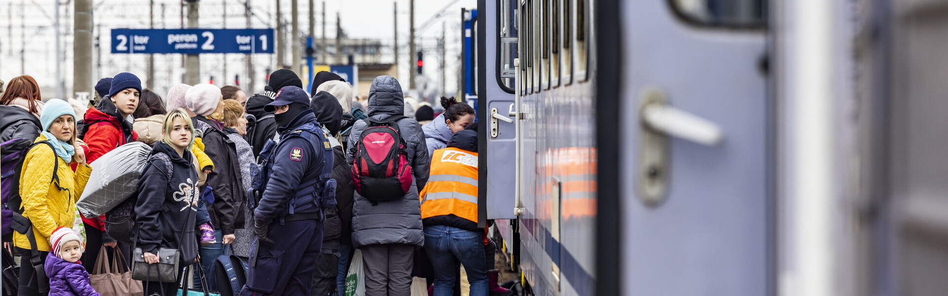 Flüchtende Menschen aus der Ukraine stehen vor einem Zug an