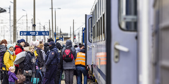 Flüchtende Menschen aus der Ukraine stehen vor einem Zug an