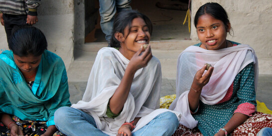 Mädchen essen vor einer Schule in Indien