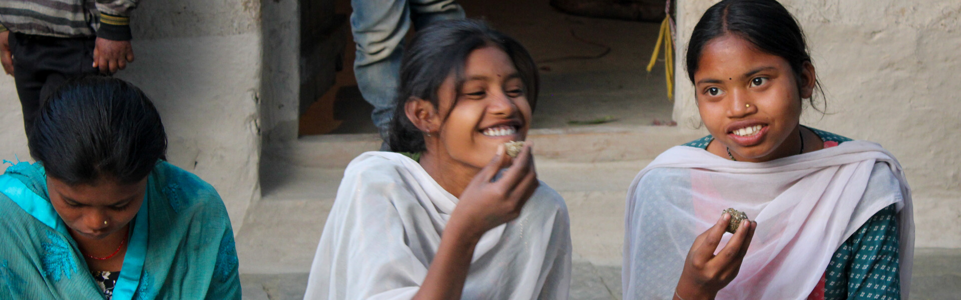 Zwei Mädchen in Indien sitzen vor einer Schule und essen