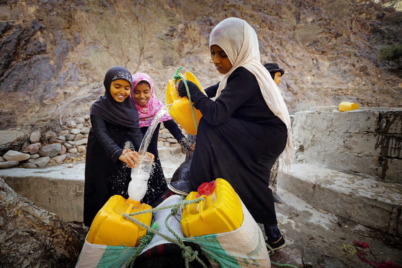 Mädchen im Jemen füllen Trinkwasser ab, das sie von einer Hilfsorganisation erhalten haben