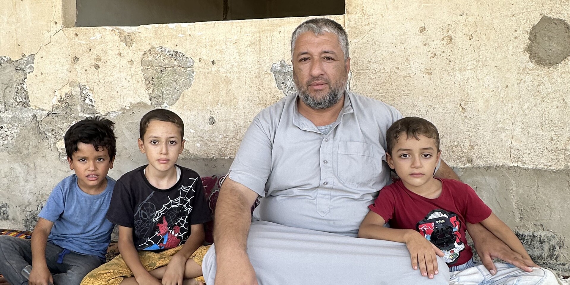 Qais Al Hmeidi sitzt mit seinen drei Kindern vor dem, was von ihrem Zuhause übrig geblieben ist Qais Al Hmeidi sitzt mit seinen drei Kindern vor dem, was von ihrem Zuhause übrig geblieben ist