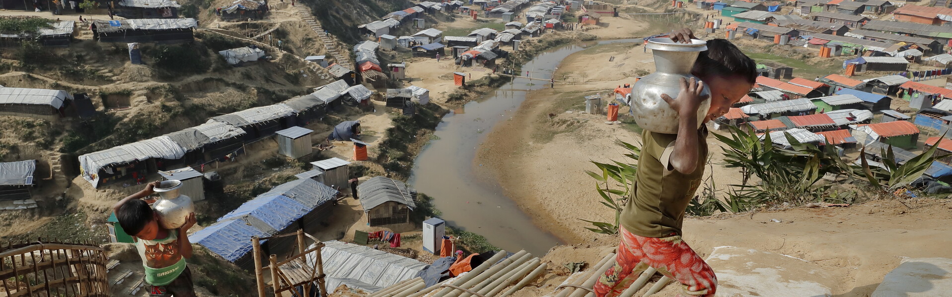 Zwei Kinder in der Flüchtlingssiedlung Cox’s Bazar in Bangladesch tragen gusseiserne Wasserkrüge eine provisorische Bambustreppe hinauf