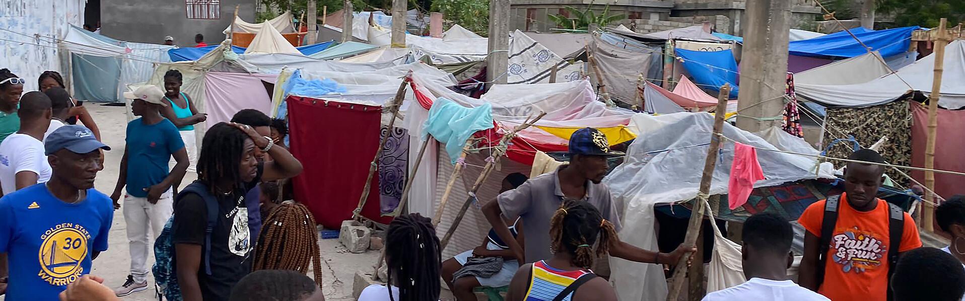Menschen in Haiti stehen vor Zelten