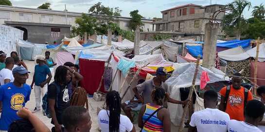 Menschen in Haiti stehen vor Zelten