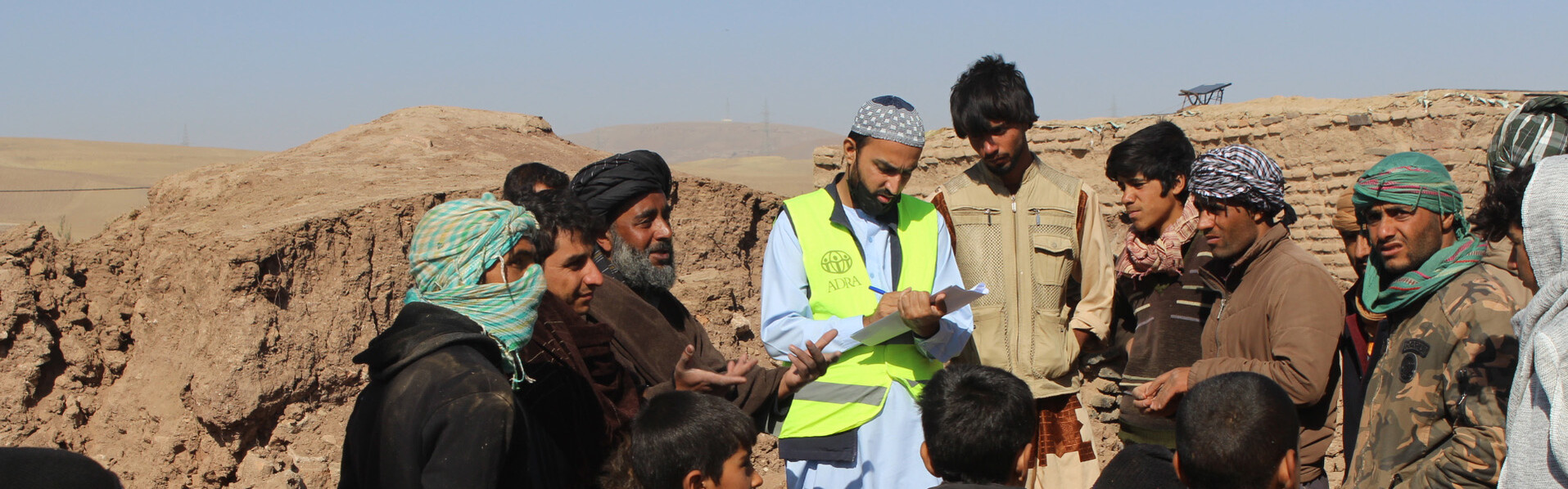 Ein ADRA-Mitarbeiter bei der Koordination von Nothilfe, umringt von einer Gruppe Männer (Symbolbild)
