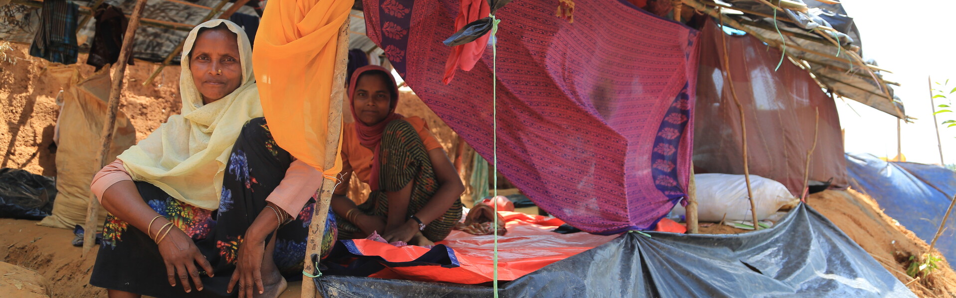 Frauen sitzen vor ihrer Notunterkunft im Flüchtlingscamp.