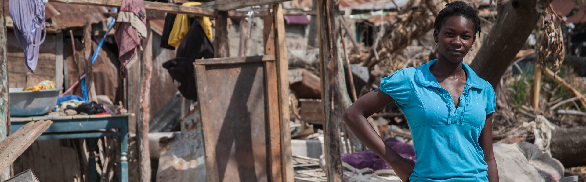 Frau steht vor einer Ruine auf Haiti nach dem Hurrikan Matthew