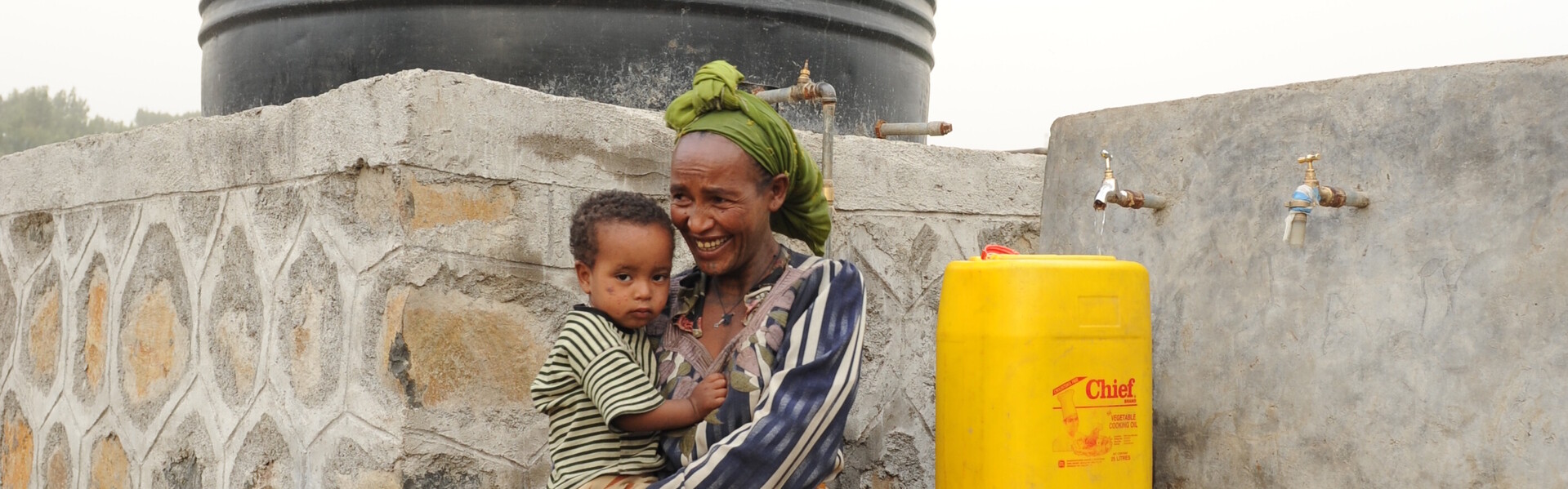 Eine Frau in Äthiopien vor der Wasserstelle unserer Bündnisorganisation Habitat for Humanity