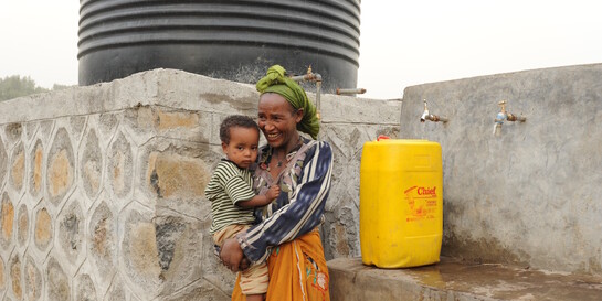 Eine Frau in Äthiopien vor der Wasserstelle unserer Bündnisorganisation Habitat for Humanity