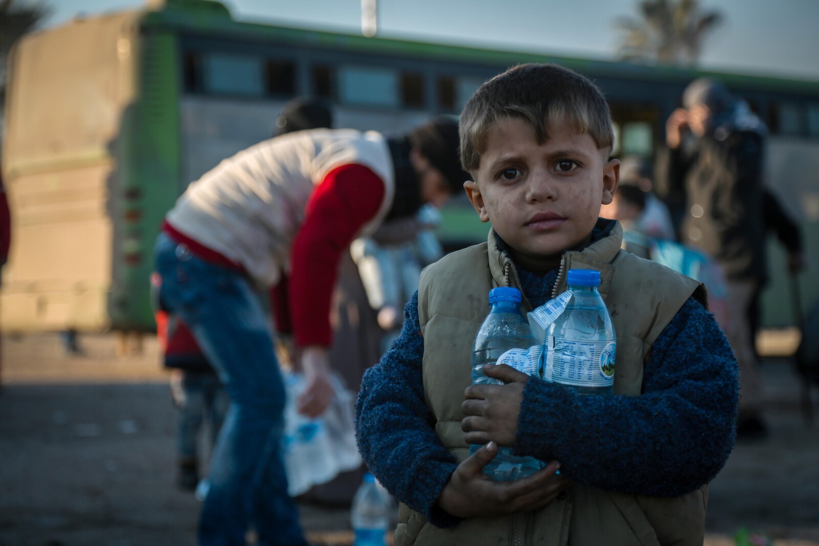 Junge steht mit Wasserfalschen in Aleppo.