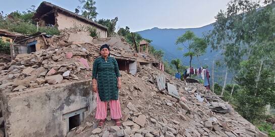 Eine Frau steht in Nepal nach dem Erdbeben auf Trümmern