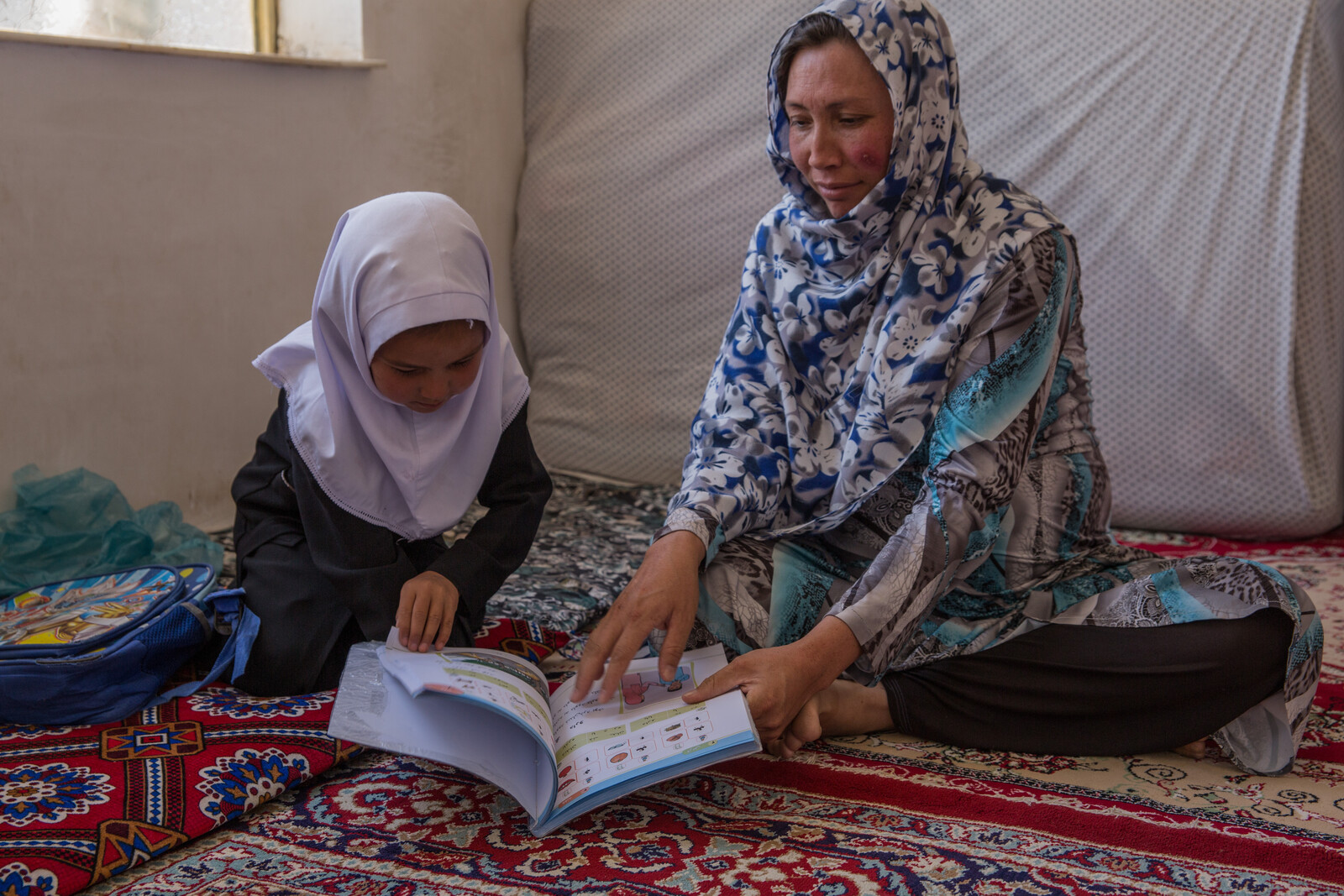 Eine Frau aus Afghanistan lernt mit ihrer Tochter das Lesen