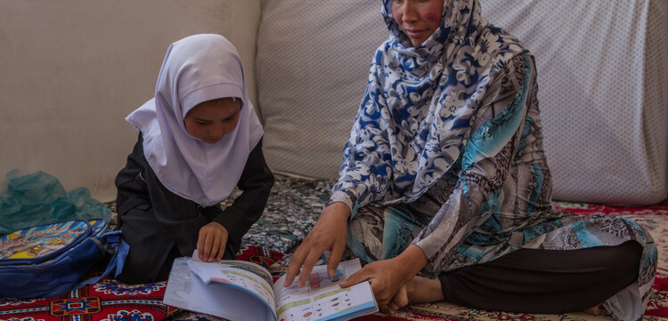 Eine Frau aus Afghanistan lernt mit ihrer Tochter das Lesen Eine Frau aus Afghanistan lernt mit ihrer Tochter das Lesen