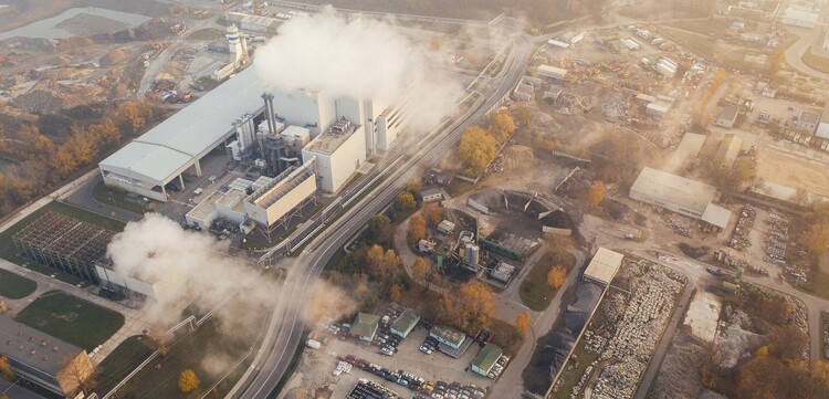 Eine Industrieanlage, die weiße Dampfschwaden in die Luft stößt 