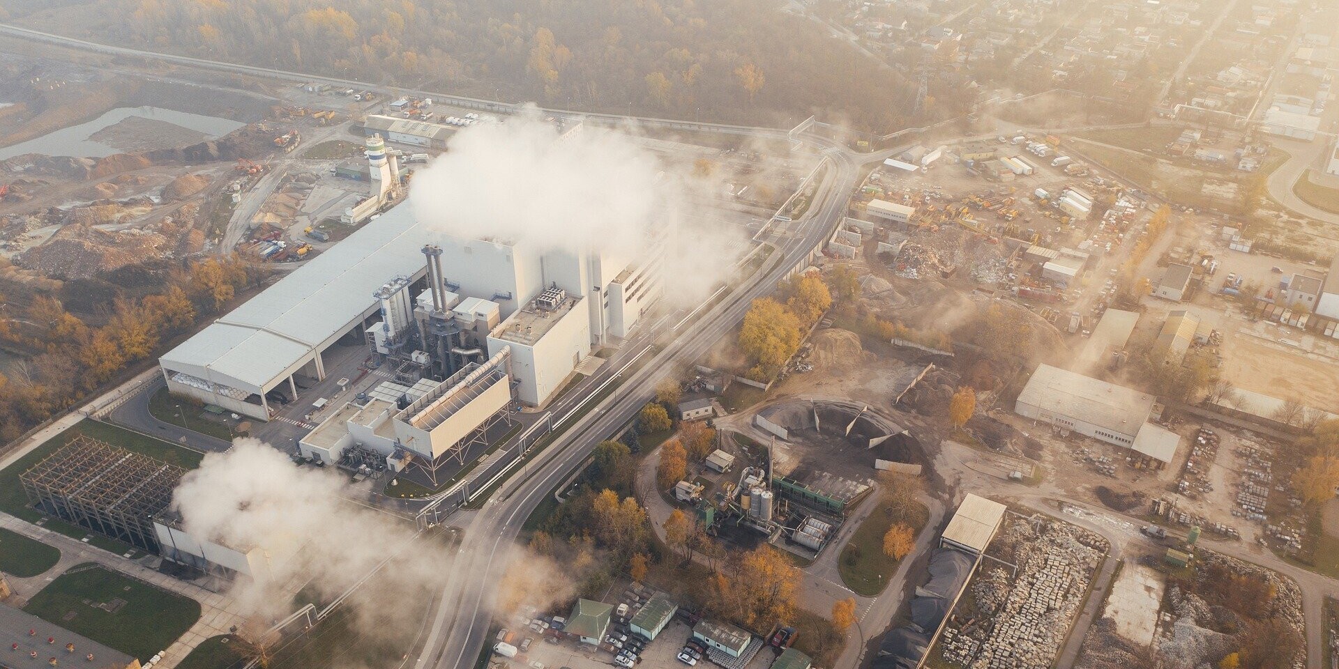 Eine Industrieanlage, die weiße Dampfschwaden in die Luft stößt 