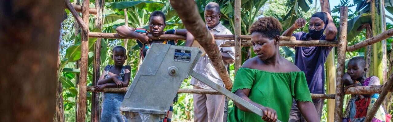 Eine Frau in Uganda pumpt Wasser in Kanister