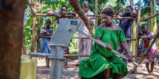 Eine Frau in Uganda pumpt Wasser in Kanister