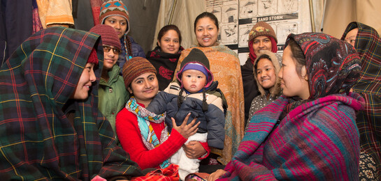 Eine Gruppe von Frauen sitzt mit einem Kind im Frauenhaus nach dem Erdbeben in Nepal.