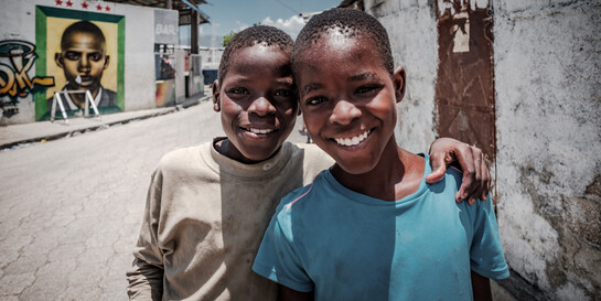 Zwei Freunde in Haiti umarmen sich.