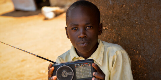 Über ein kleines tragbares Radio empfängt Samuel aus Uganda die neuesten Meldungen zum Coronavirus