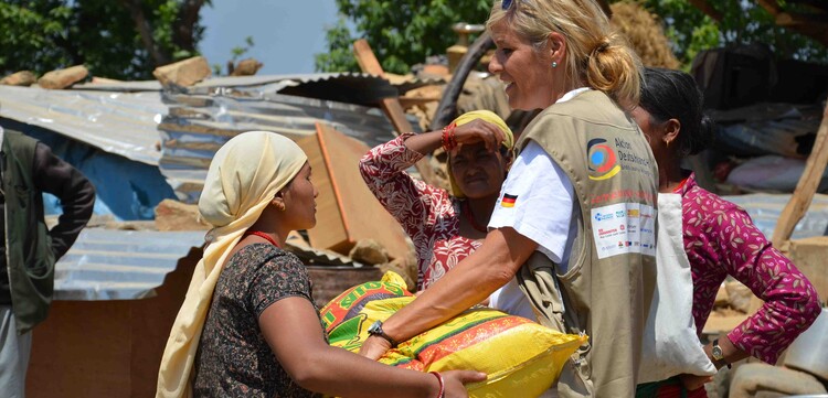 Nach dem schweren Erdbeben in Nepal werden erste Hilfsgüter verteilt. Eine Frau erhält Nahrungsmittel von einer Helferin.