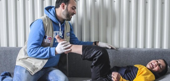 Ein Physiotherapeut macht Übungen mit einem verletzten Jungen. Handicap International hilft in Jordanien verletzten und traumatisierten Menschen.