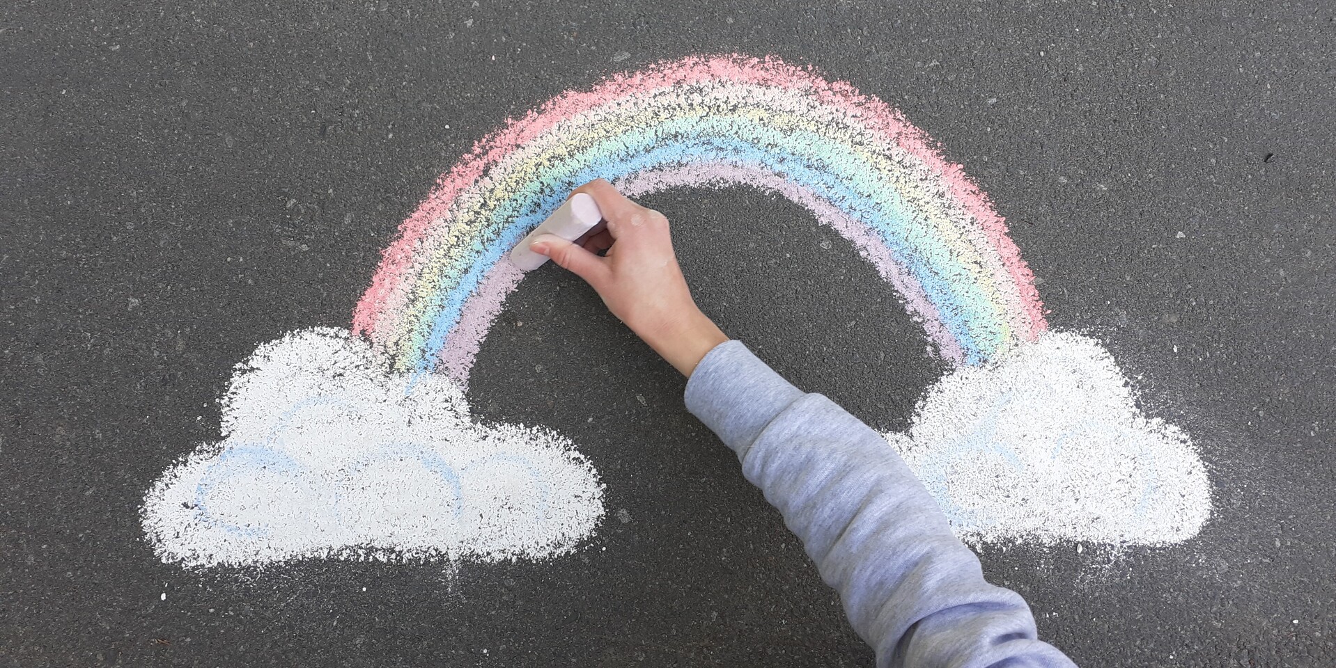 Hoffnung schenken während Corona: Ein Kind malt einen Regenbogen auf den Asphalt. Hoffnung schenken während Corona: Ein Kind malt einen Regenbogen auf den Asphalt.