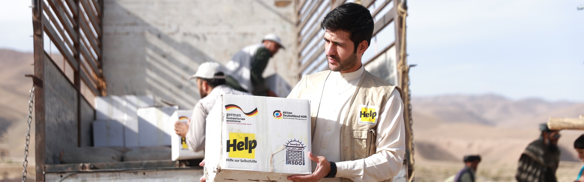 Ein Helfer von Help - Hilfe zur Selbsthilfe lädt Hilfsgüter aus einem Lastwagen