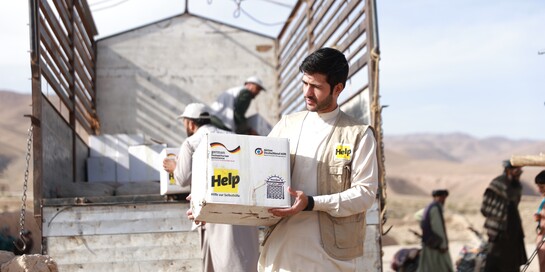 Helfer von Help - Hilfe zur Selbsthilfe laden Hilfsgüter aus einem Lastwagen