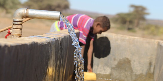 Ein Junge in Somalia schöpft Wasser aus einem Brunnen
