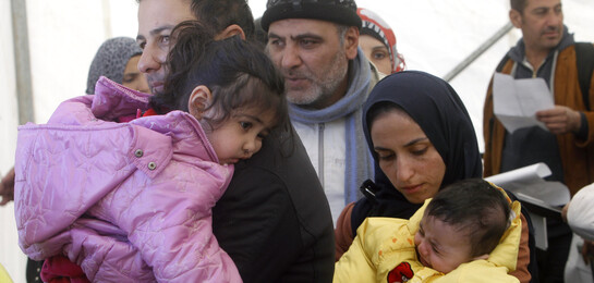 Eine Familie steht mit Kindern im Arm in Syrien.
