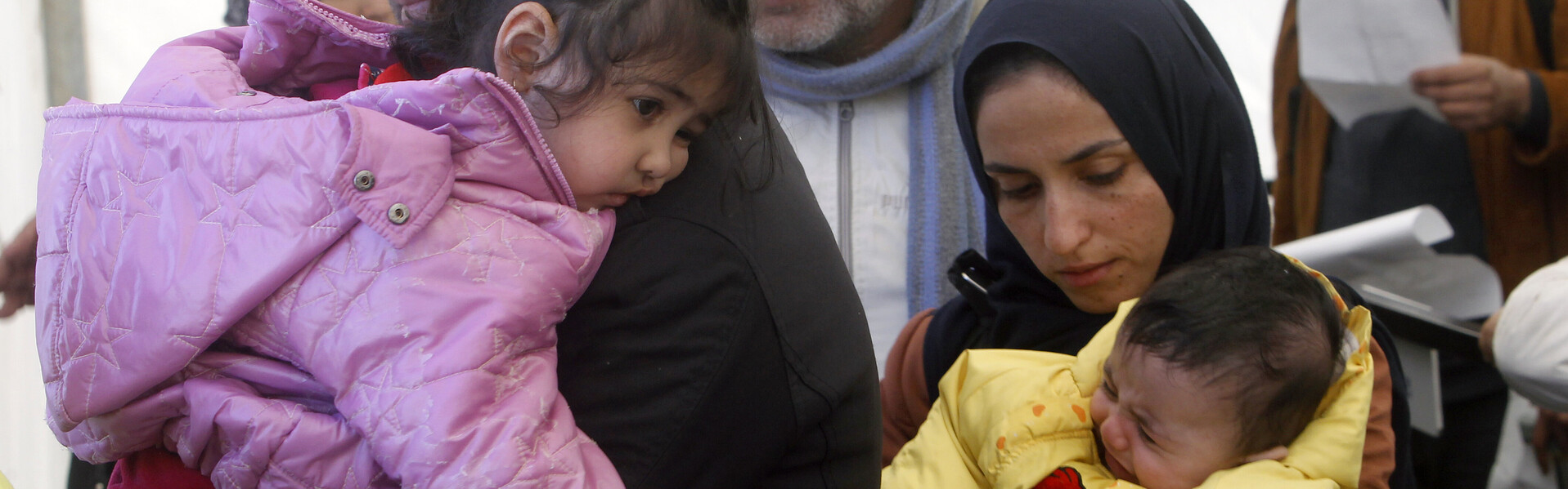 Eine Familie steht mit Kindern im Arm in Syrien.
