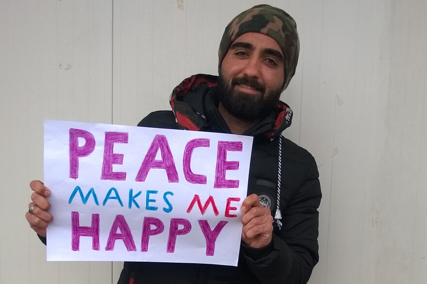 Ein junger Mann in Nordirak mit einem Schild in der Hand.