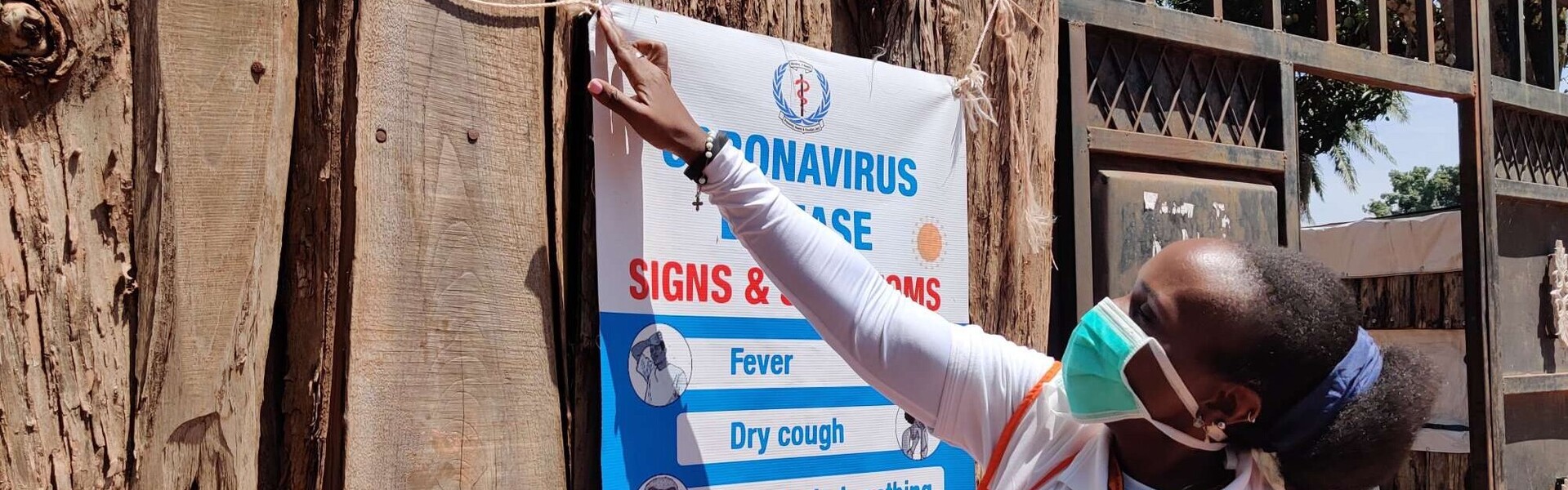 Eine Gesundheitshelferin von World Vision hängt im Südsudan ein Plakat über die Corona-Symptome auf