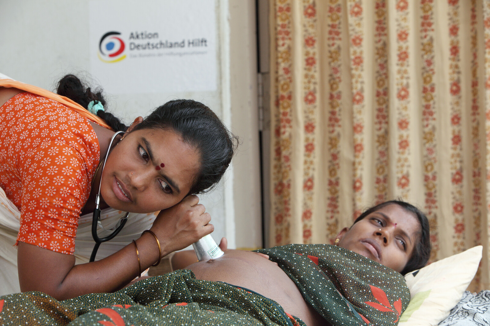 Eine Krankenschwester in Indien hört den Bauch einer schwangeren Frau ab