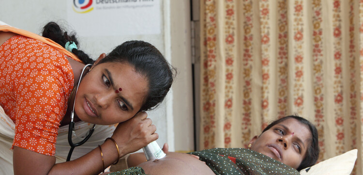 Eine Krankenschwester in Indien hört den Bauch einer schwangeren Frau ab Eine Krankenschwester in Indien hört den Bauch einer schwangeren Frau ab