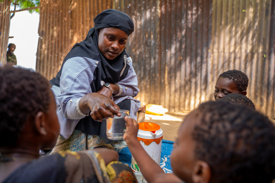 Eine Frau gibt einem Kind ein Glas Wasser