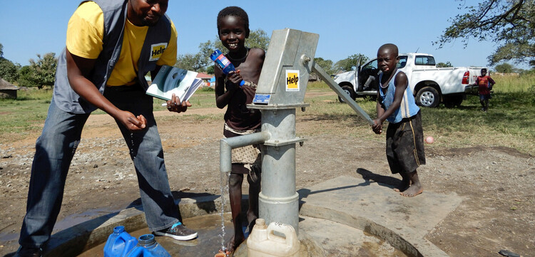 Humanitärer Helfer zeigt Kindern einen Brunnen Humanitärer Helfer zeigt Kindern einen Brunnen