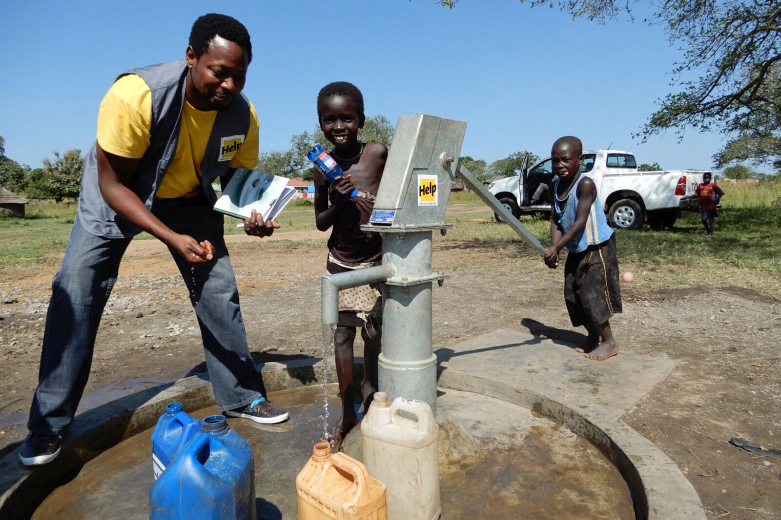 Humanitärer Helfer zeigt Kindern einen Brunnen