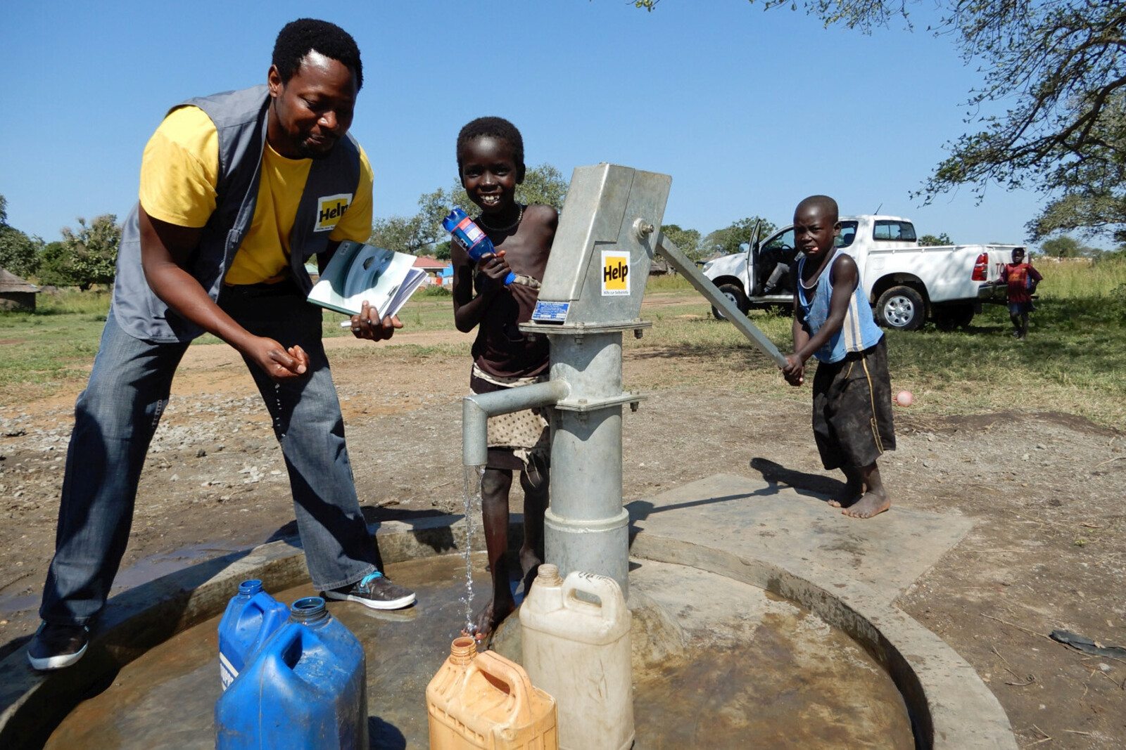 Humanitärer Helfer zeigt Kindern einen Brunnen