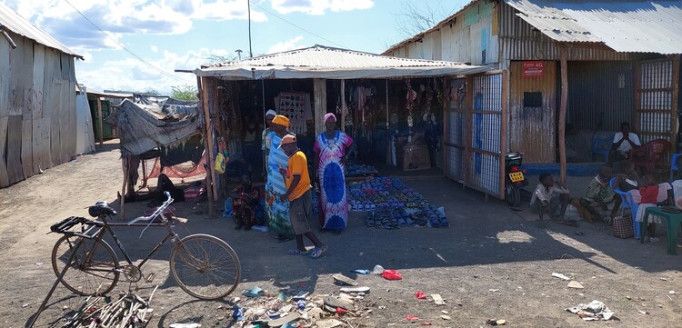 Menschen stehen vor einer Hütte im Geflüchtetencamp in Kakuma, Kenia Menschen stehen vor einer Hütte im Geflüchtetencamp in Kakuma, Kenia