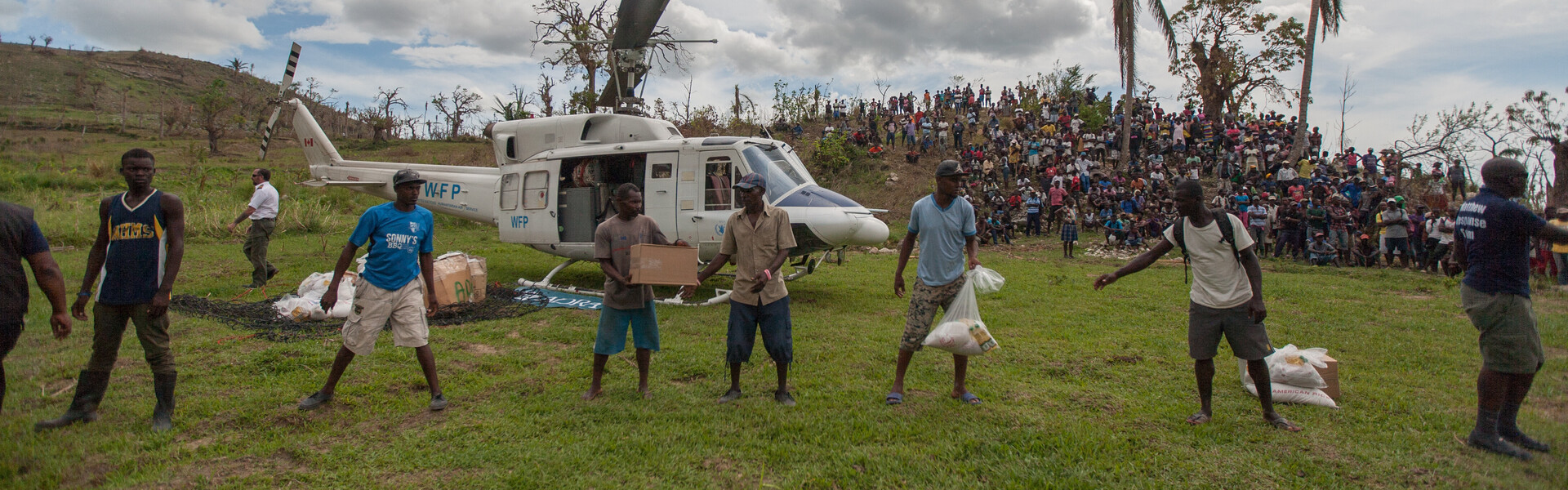 Helfer von der Hilfsorganisation ADRA verteilen Nothilfepakete aus einem Helikopter an die Betroffenen des Hurrikan Matthew in Haiti